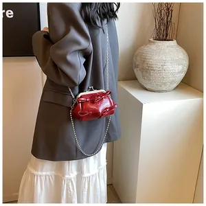 Dettaglio mini borsa a catena rosso vino con fiocchi su blazer grigio e gonna