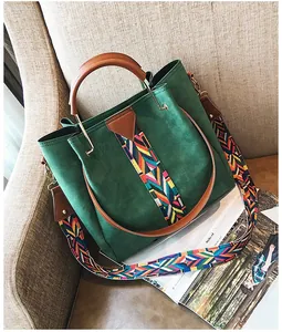Detailed close-up of dark green suede tote with patterned strap on a magazine