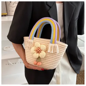 Dettaglio borsa in paglia beige tessuta a mano con manico colorato e girasole in peluche