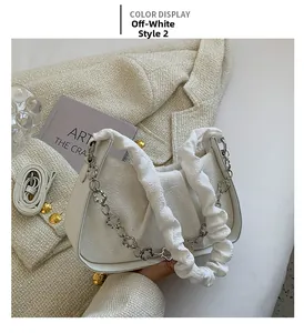 Dettaglio borsa a pieghe bianco crema con catena floreale argentata e trama in tessuto