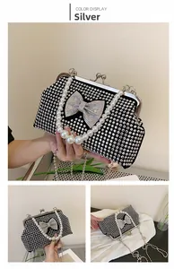 Detail of silver evening clutch bag with rhinestone bow decoration and pearl handle