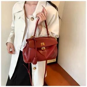 Dettaglio della borsa in pelle rosso scuro con chiusura dorata e superficie testurizzata