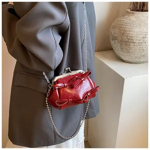 Dettaglio della mini borsa a conchiglia rosso vino con fiocchi e catena in argento