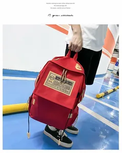 Dettaglio dello zaino per studenti in nylon rosso con toppa vintage e chiusura a lacci