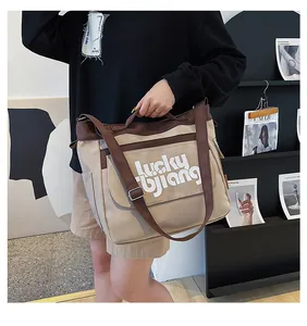 Dettaglio della grande borsa messenger in tela con inserti kaki marroni e logo Lucky bjiang