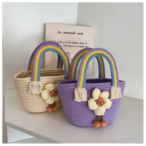 Dettaglio borsa in paglia con manico arcobaleno, fiore in tessuto e ciondolo a ciliegia