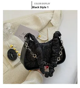 Dettaglio borsa a spalla plissettata nera con catena a fiori argento su tessuto tweed