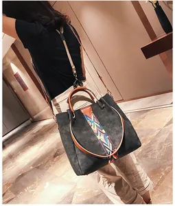 Close-up of a large grey tote bag with colorful ethnic embroidery strap on model