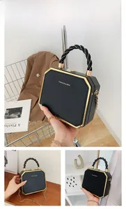 Detail of black acrylic octagonal handbag with gold trim and braided handle