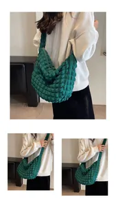 Détail de la texture plissée vert émeraude et du design incurvé du sac à bandoulière