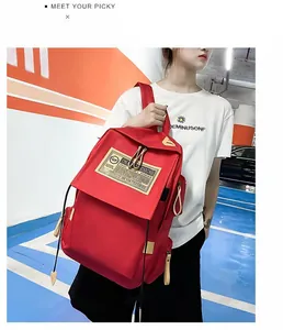 Dettaglio di uno zaino rosso in nylon resistente all'acqua con patch beige e lacci decorativi