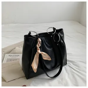 Detail of black crocodile pattern tote bag with silver metal handle and silk scarf detail