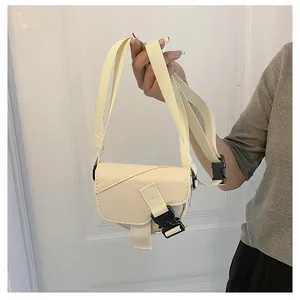 Dettaglio della mini borsa a sella in nylon bianco crema con trama e fibbia sulla tracolla