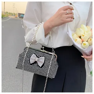 Detail of black rhinestone evening clutch with pearl handle and sparkling diamond bow