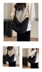 Détail du tissu gaufré noir sur un sac à bandoulière en forme de croissant spacieux