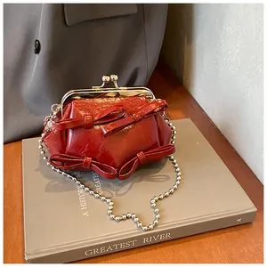 Dettaglio mini borsa in pelle lucida rossa con fiocchi e tracolla a catena