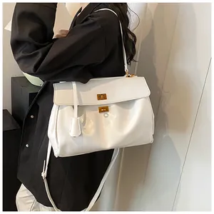 Dettaglio della pelle bianca e delle chiusure dorate a scatto sulla borsa tote