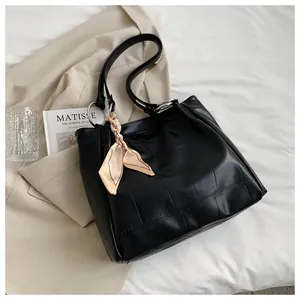 Detail of black faux leather tote with crocodile pattern, silk scarf, and metal rings