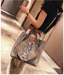 Detailed view of grey tote bag featuring colorful woven strap and brown leather handles