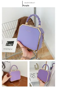 Detail of purple acrylic box bag with golden metal trim and chain strap