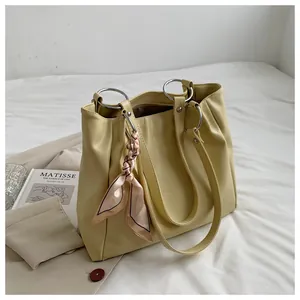 Detail of crocodile embossed cream tote bag with gold ring handles and pink silk scarf