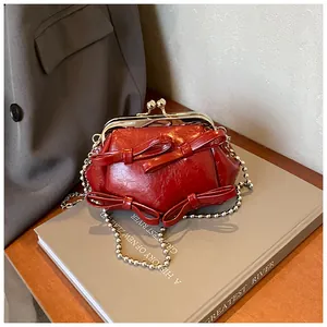 Dettaglio borsa vintage rossa con fiocchi e tracolla a catena con sfere d'argento