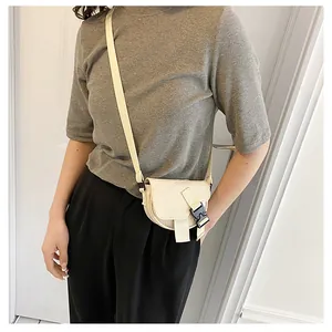 Dettaglio della mini borsa a sella in nylon bianco crema con fibbia tattica e tracolla