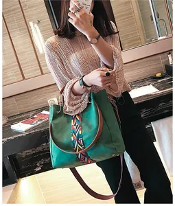 Detail of dark green tote bag with ethnic woven strap and brown leather handles