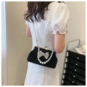 Close-up of black beaded clutch bag with rhinestone bow and white pearl handle detail
