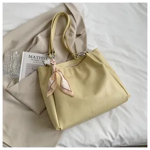 Close-up of pale yellow crocodile pattern tote bag with decorative floral scarf handle