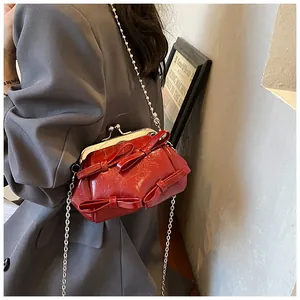 Dettaglio della borsa bordeaux con fiocco e catena d'argento su un blazer grigio