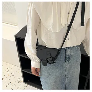 Vista indossata di una mini borsa a tracolla in nylon nero con patta e fibbia a scatto