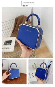 Detail view of royal blue acrylic box bag with golden trim and twisted top handle strap