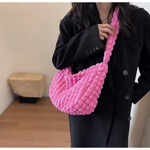 Gros plan du sac à bandoulière rose plissé à texture pop-corn porté par un mannequin