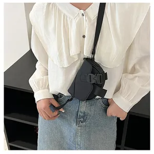 Dettaglio di una mini borsa a tracolla in nylon nero indossata da una modella in stile casual