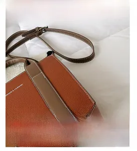 Detail of orange-brown pebble leather tote showing silver rivets and stitching