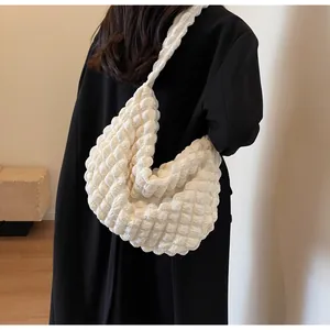 Vue détaillée du sac à bandoulière blanc plissé 3D effet popcorn sur un manteau noir