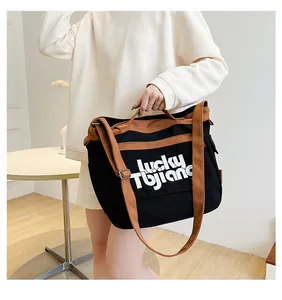 Dettaglio della grande borsa in tela con scritta lucky Tujiano e tracolla regolabile