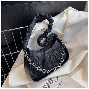 Dettaglio borsa nera a pieghe con catena floreale argento e manico stile scrunchie