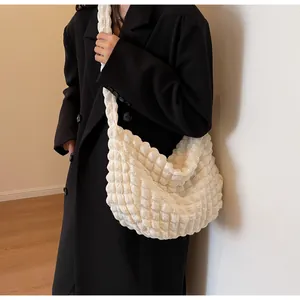 Détail de la texture gaufrée blanche en tissu et de la large bandoulière du sac à main