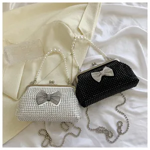 Detail of rhinestone bow and pearl handle on elegant silver and black party clutch bags