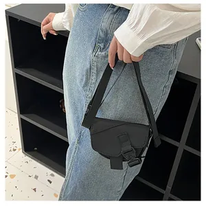 Dettaglio mini borsa a sella in nylon nero con tracolla e fibbia tattica regolabile