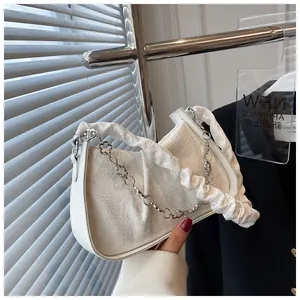 Dettaglio borsa baguette bianca in tessuto goffrato floreale con catena di prugna