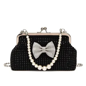 Macro shot of black beaded evening clutch featuring a sparkling rhinestone bow and pearl strap