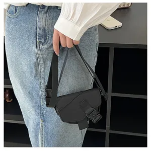 Dettaglio di una mini borsa a tracolla in nylon nero con una grande fibbia in plastica