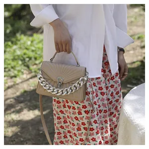Dettaglio borsa trapuntata beige con catena decorativa argentata e chiusura a ferro di cavallo