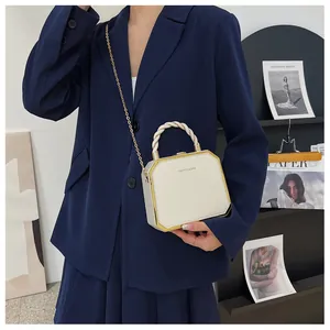 Chic cream acrylic box bag with gold chain strap shown on a navy blue blazer outfit