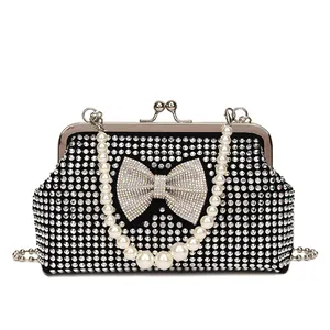 Elegant black evening clutch with rhinestone bow, pearl handle, and silver chain strap