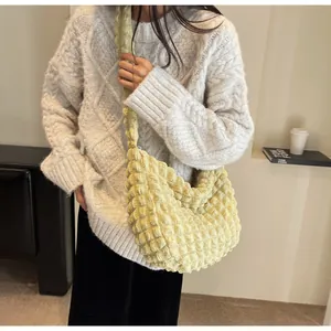 Détail du sac à bandoulière jaune clair plissé avec texture gaufrée sur mannequin