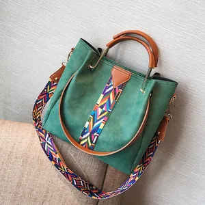 Dark green suede bucket bag with brown leather handles and ethnic geometric shoulder strap